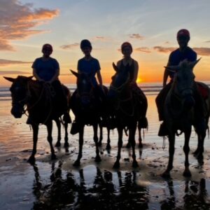 Family horseback riding on the beach at sunset in Costa Rica