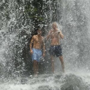 Teenage boys behind Nauyaca Waterall on vacation in Costa Rica