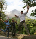 a family jumping with excitement with a view of the Arenal Volcano in the background