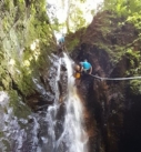 a young woman using AFOs rappelling down a waterfall side by side with a canyoning guide on an accessible adventure in Costa Rica