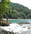 serendipity adventures client standing on a rocky point on the rainforested coastlined on an adventure in Costa Rica