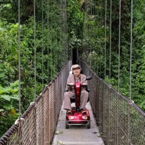 Senior travelers with a motorized scooter on a hanging bridge in Costa Rica