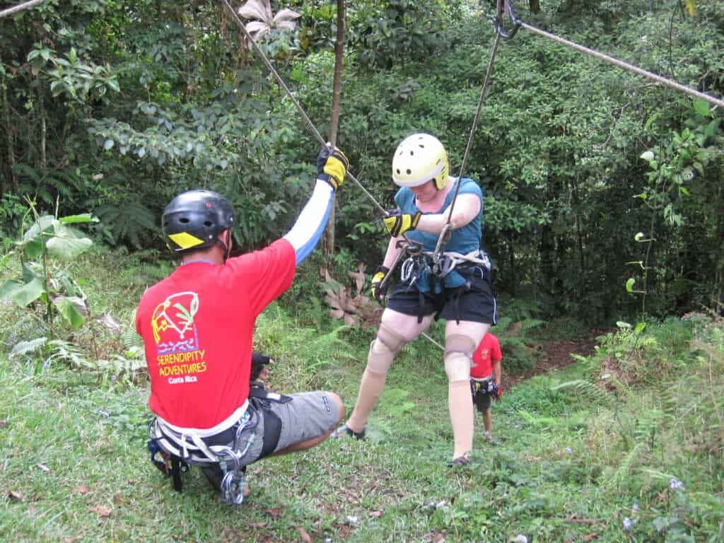 disabled traveler with two prosthetic legs practicing rappelling with two instructors